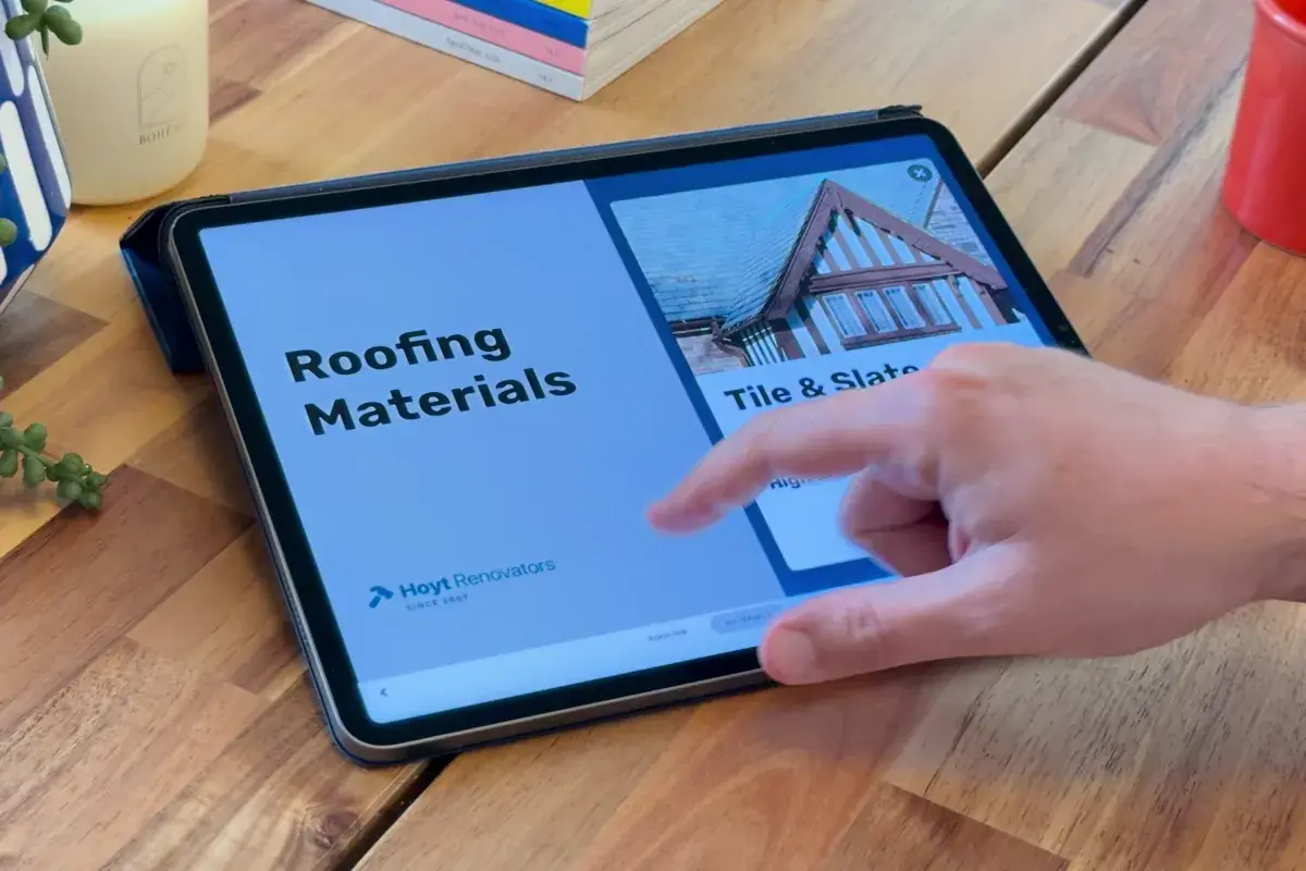 An Ingage roofing presentation open on an iPad at a homeowner's kitchen table, a hand mid-tap on the screen.